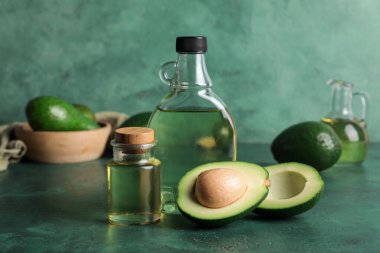 Yeşil arka planda avokado yağı şişeleri