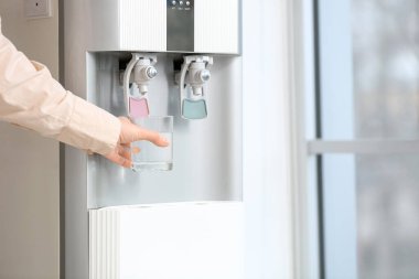 Kadın elleri arka planda serinletici sulardan su dolduruyor