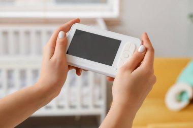 Çocukların yatak odasında elinde bebek telsizi olan bir kadın var.