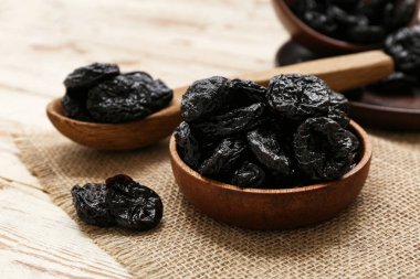 Beyaz ahşap arka planda kuru erikli kase ve kaşık.