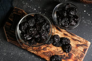 Siyah arka planda kurumuş kuru erikli cam kaseler.