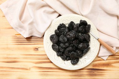 Kurutulmuş kuru erik ve ahşap zemin üzerinde kaşık tabağı