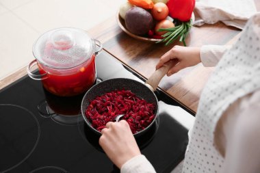 Mutfakta sebze kızartan genç bir kadın.