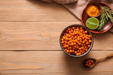 Lezzetli kızarmış nohut, biberiye ve ahşap arka planda limon kâsesi.