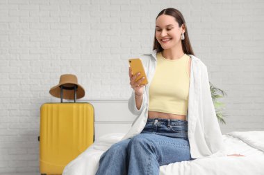 Otel odasında cep telefonu kullanan kadın turist.