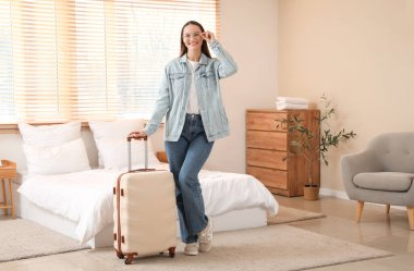 Otel odasında bavullu bir kadın turist.