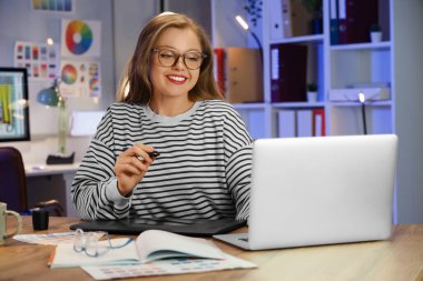 Geceleri grafik tablet ve dizüstü bilgisayarla çalışan kadın tasarımcı