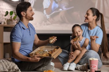 Evde film izlerken lezzetli pizzalı aile.