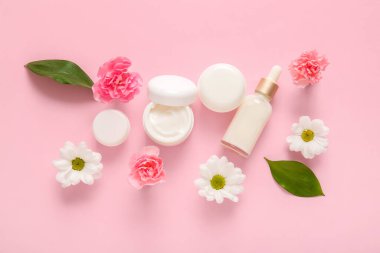 Farklı kozmetik ürünleri ve pembe arka planda güzel çiçekler.