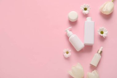 Farklı kozmetik ürünleri ve pembe arka planda güzel çiçekler.