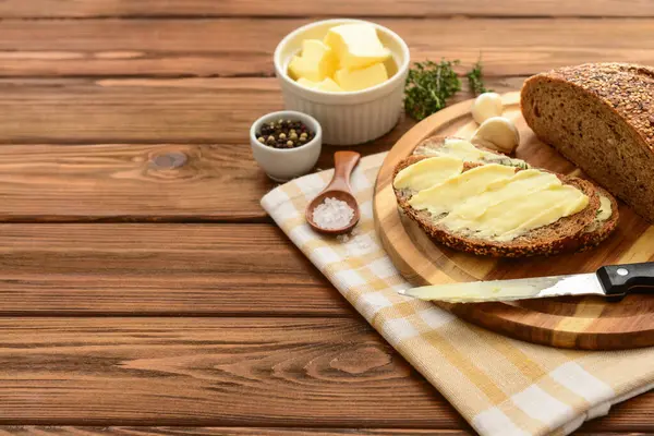 Taze ekmek, farklı baharatlar ve ahşap arka planda bir kase tereyağı.