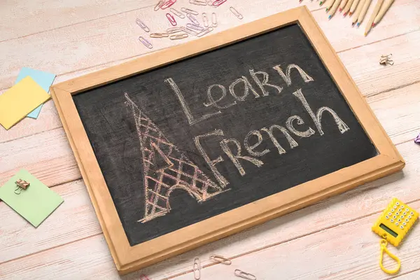 Metin LeARN FRENCH ve hafif ahşap zemin üzerinde farklı kırtasiye malzemesi içeren tebeşir tahtası