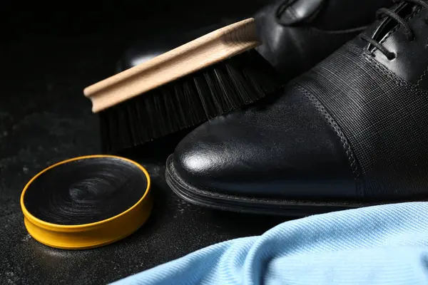 Siyah arka planda fırçalar, ayakkabılar, kumaşlar ve ayakkabı cilası