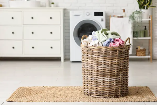 Çamaşır makinesinin yanında çamaşır sepeti var.