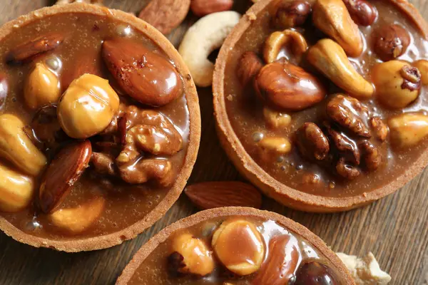 Kahverengi tahta üzerinde fındıklı ve karamel soslu lezzetli tartlar.