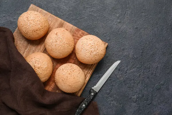 Koyu arkaplanda susam tohumları olan tahtadan taze çörekler.