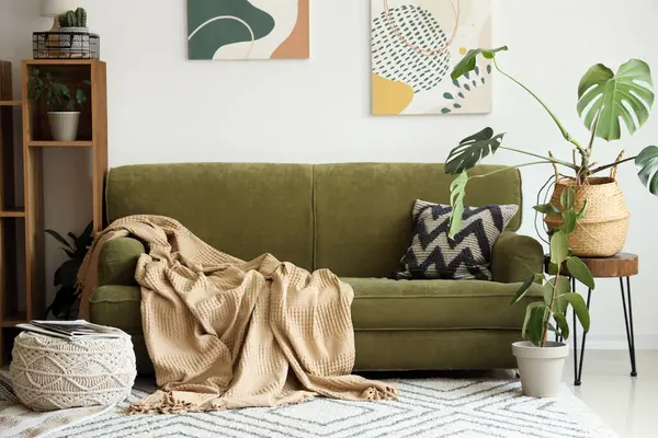 Beyaz duvarın yanında yeşil kanepesi ve raf ünitesi olan modern bir oda.