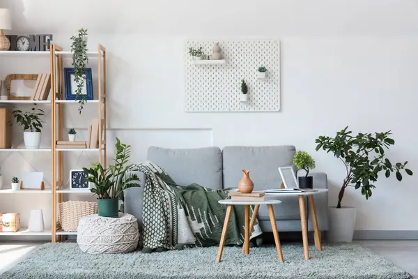 Gri kanepesi, raf ünitesi ve sehpaları olan modern oturma odasının içinde.
