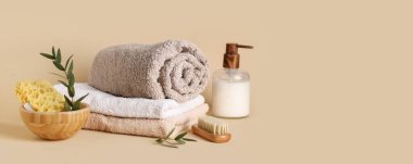 Bej arka planda yumuşak havlular ve bir şişe kozmetik ile spa kompozisyonu ve metin için boşluk