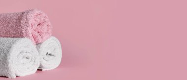 Pembe zemin üzerinde yuvarlanmış yumuşak havlular ve metin için boşluk