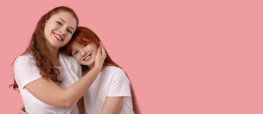 Mutlu kızıl saçlı kadın pembe arka planda mesaj atmak için kızını kucaklıyor. Anneler Günü kutlaması