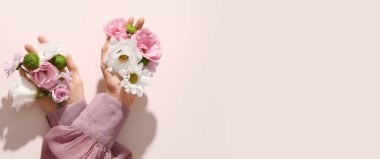 Pembe arka planda farklı taze çiçekleri tutan kadın elleri metin için yer açıyor.