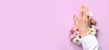 Metin ve üst görünüm için alanı olan leylak arkaplan üzerinde kadın eli ve çiçekler