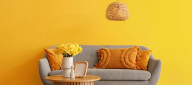 Oturma odasındaki sehpanın üzerinde nergis çiçekleri olan vazo.