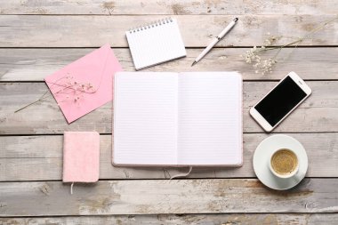 Not defterleri, cep telefonu ve yıpranmış ahşap masada bir fincan kahve ile kompozisyon