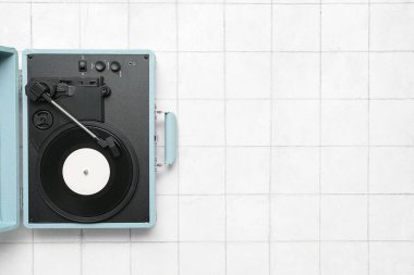 Beyaz karo zemin üzerinde vinil diski olan kayıt oynatıcı