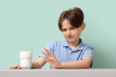 Laktoz toleransı olmayan küçük çocuk turkuaz arka planda masada oturuyor.