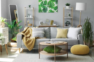 Gri kanepesi, çiçekleri ve aynası olan modern oturma odası.