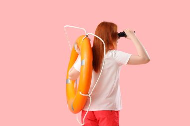 Yüzük şamandırası ve pembe arka planda dürbünü olan kadın cankurtaran.