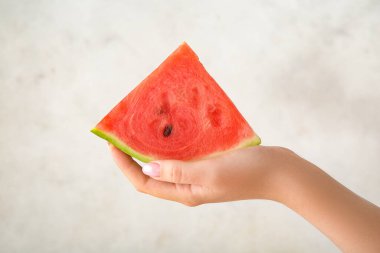 Arkaplanda olgun bir karpuz parçasıyla kadın eli, yakın plan.