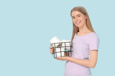 Elinde tuvalet kağıdı ruloları olan sepet tutan genç bir kadın.