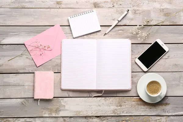 Not defterleri, cep telefonu ve yıpranmış ahşap masada bir fincan kahve ile kompozisyon
