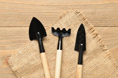 Ahşap arka planda bahçıvan tırmığı ve kürekler.