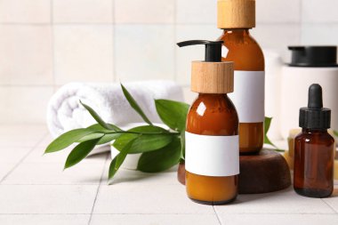 Şampuan şişeleri ve beyaz fayans zemininde gerekli yağ.