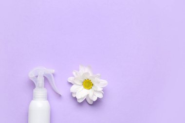 Bir şişe kozmetik ürünü ve leylak arkaplanda papatya çiçeği.