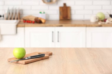 Mutfaktaki masada elma ve bıçakla kesme tahtası.