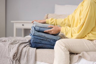 Bir yığın elbisesi olan kadın yatak odasında oturuyor, yakın plan.