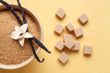 Aromatik vanilya şekeri, çiçek ve sarı zemin üzerine yapışmış bir kase.