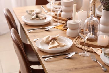 Katlanmış peçeteler, çatal bıçak takımı ve tabakları olan zarif bir masa.