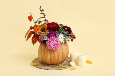 Balkabağında güzel sonbahar buketi ve sarı arka planda yanan mumlar.