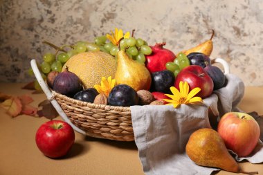 Bej arka planda farklı taze meyvelerle dolu bir sepet.