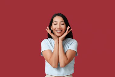 Genç Asyalı kadın kırmızı arka planda gülüyor