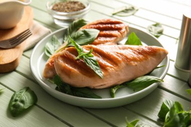 Lezzetli ızgara tavuk göğsü ve yeşil ahşap arka planda fesleğen.