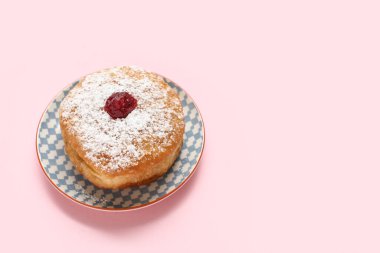 Pembe arka planda Hanuka kutlaması için lezzetli donutla tabak.