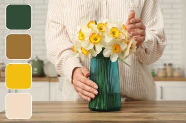 Şık bir mutfakta, sarı çiçekli vazoya dokunan genç bir kadın.