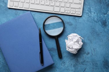 Kitap, kalem, büyüteç, klavye ve arka planda buruşmuş kağıt top, yakın plan. Dünya Şiir Günü Kutlaması